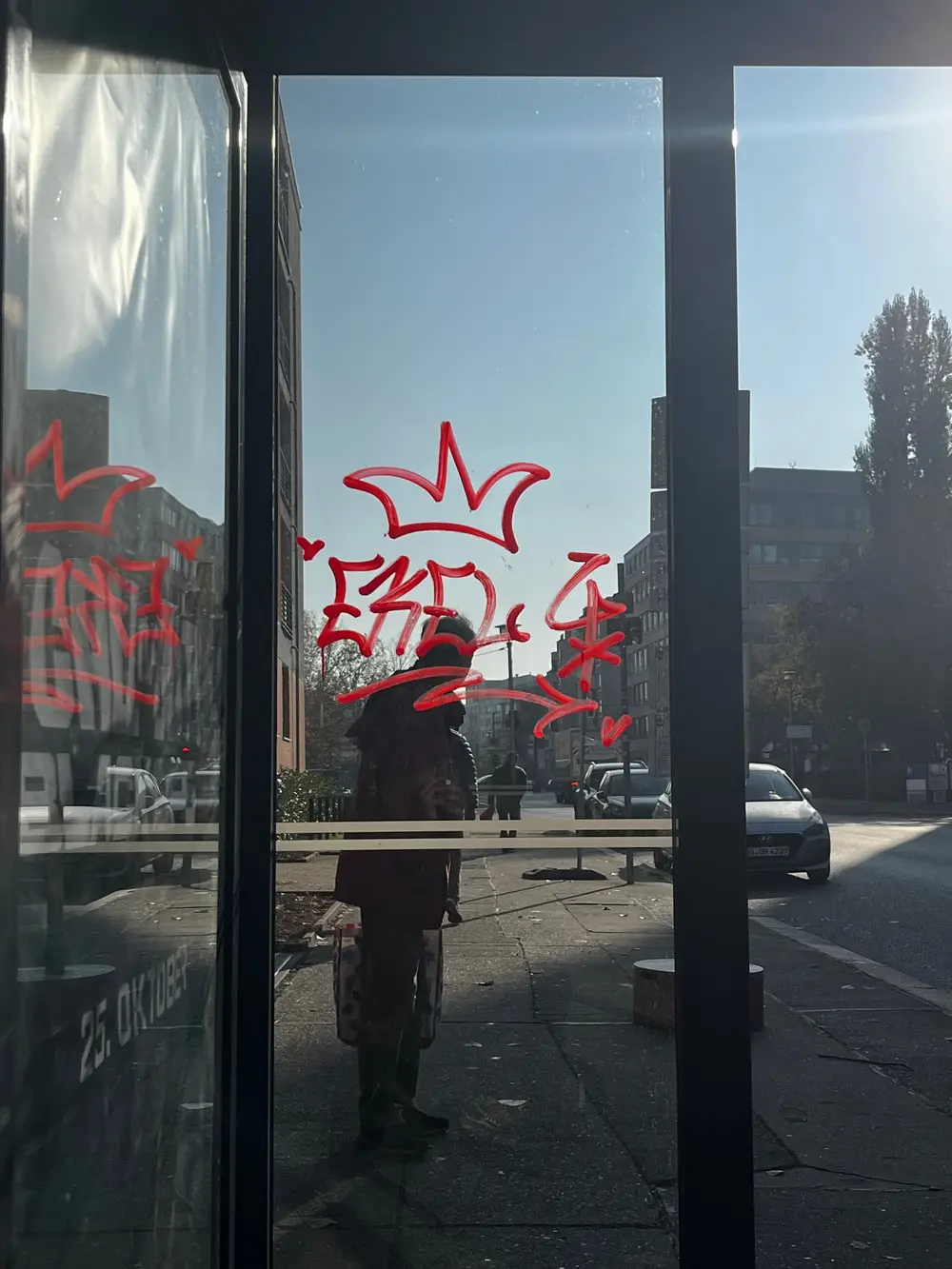 Red graffiti on glass doors lit by the low afternoon sun.