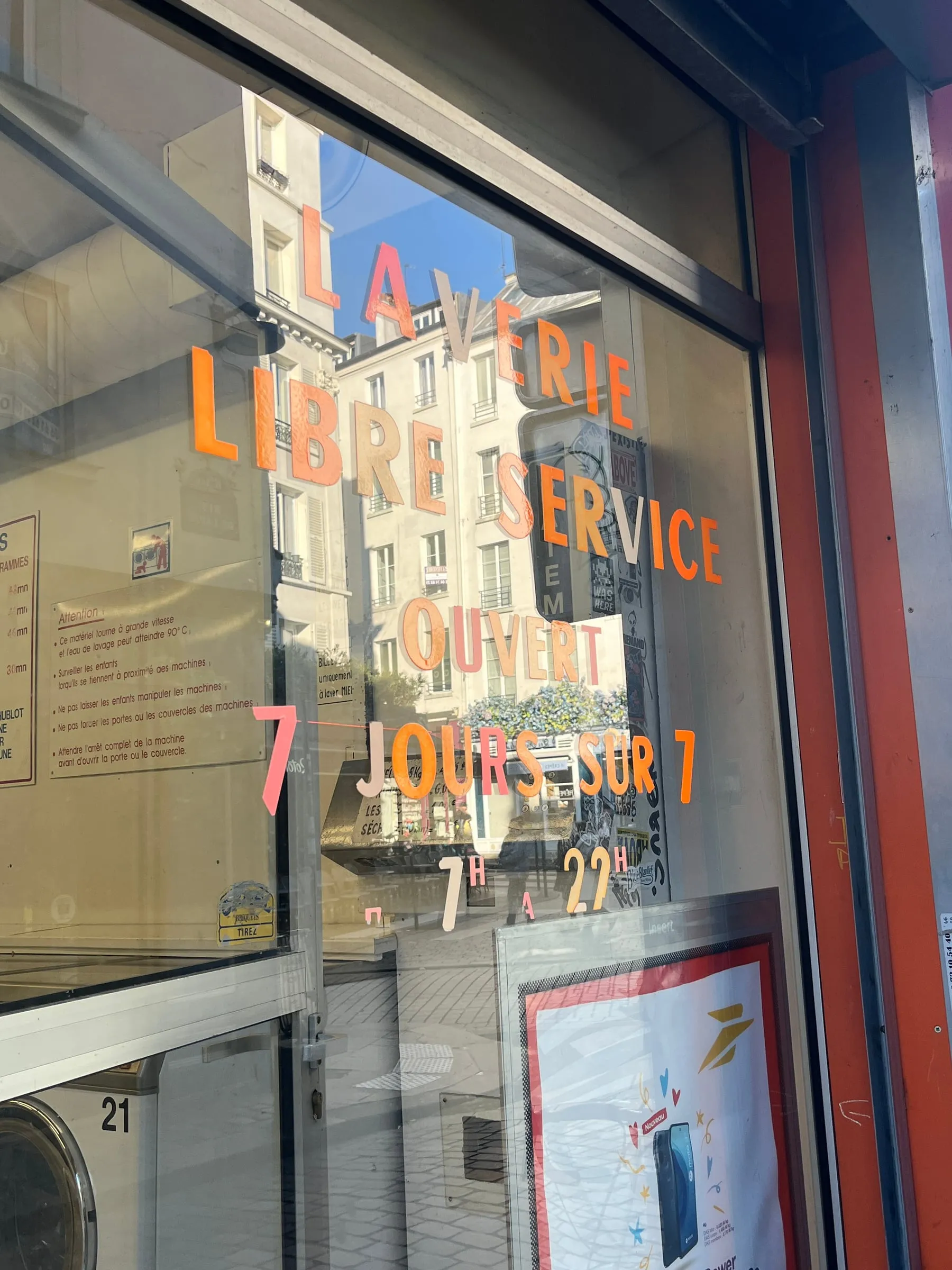 Painted lettering on a bookshop window reflecting the buildings across the street.