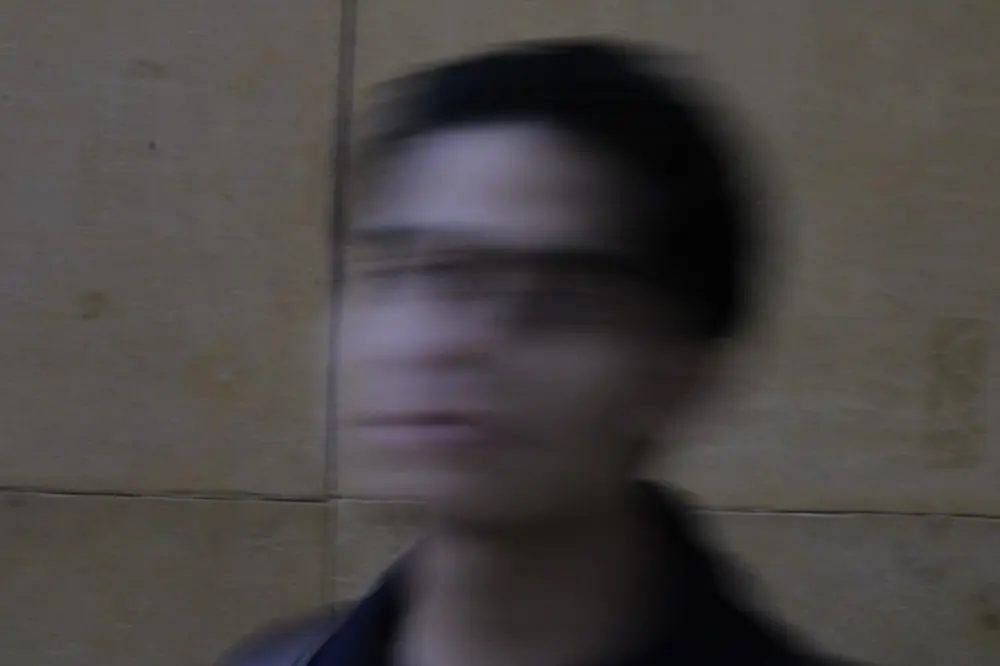 A motion-blurred portrait in front of a beige stone wall.