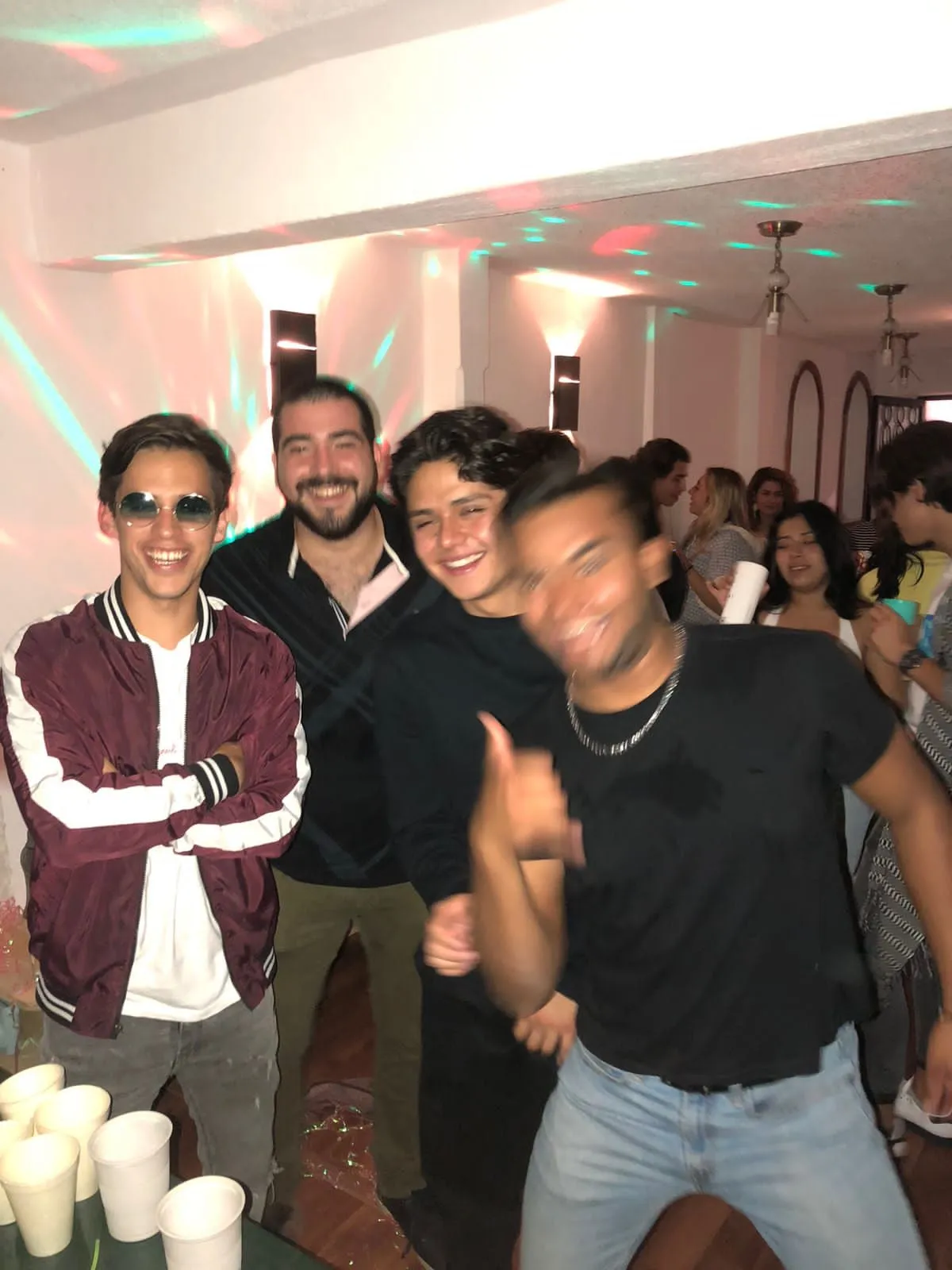 Four people smiling and posing together at an indoor gathering.