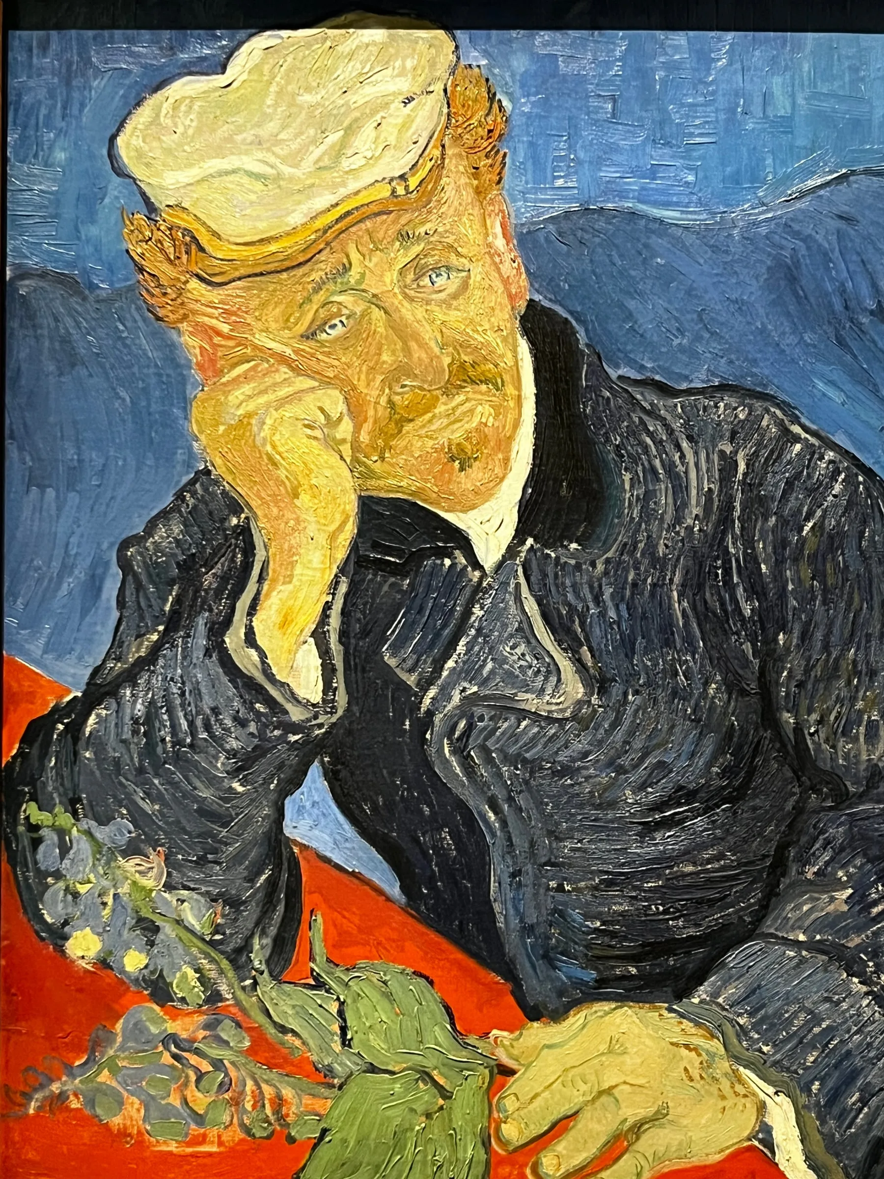 A painting of a man resting his head on one hand beside flowers and books.