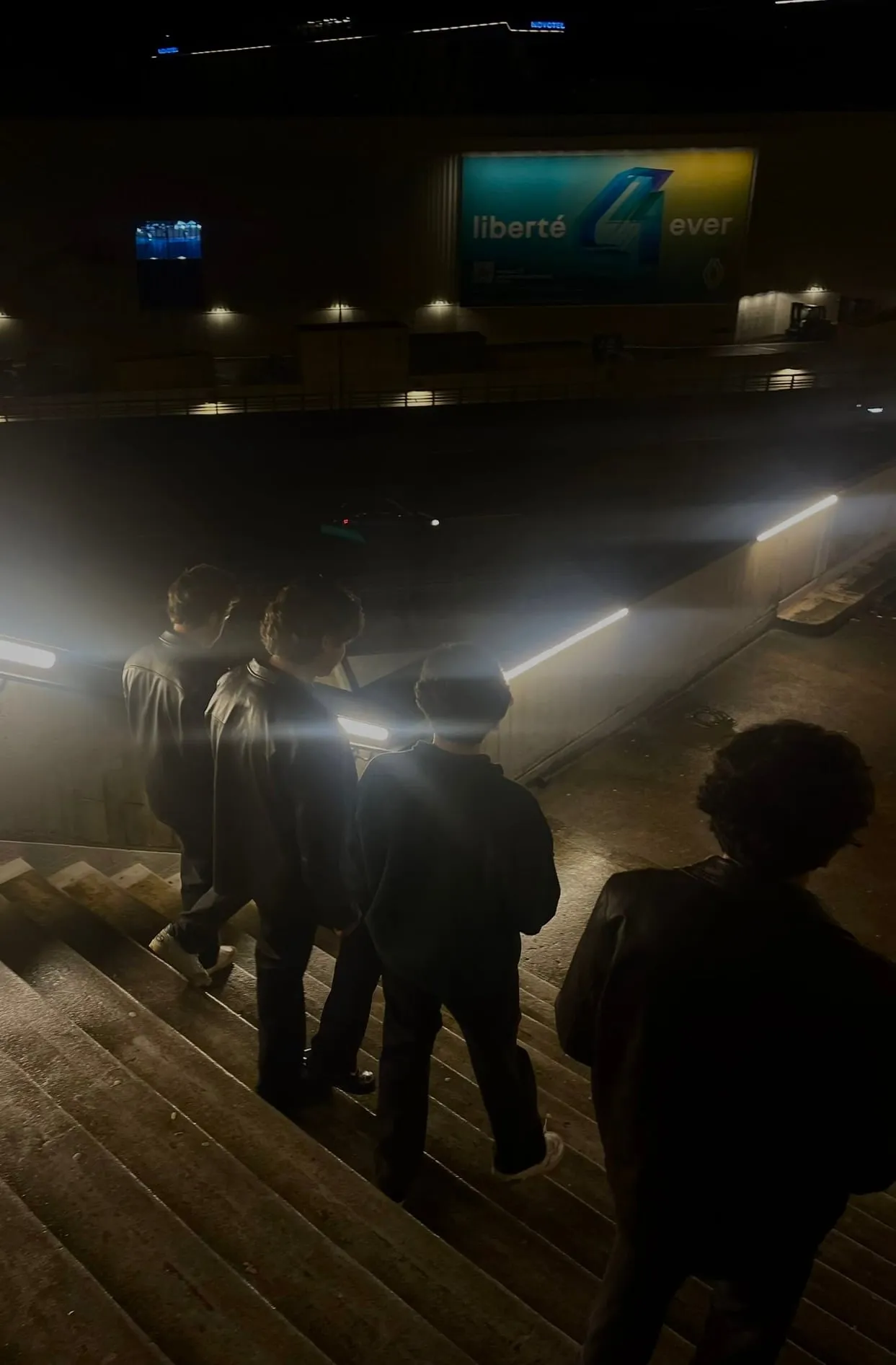 A group descending steps in the dark, with small lights shining toward the camera.