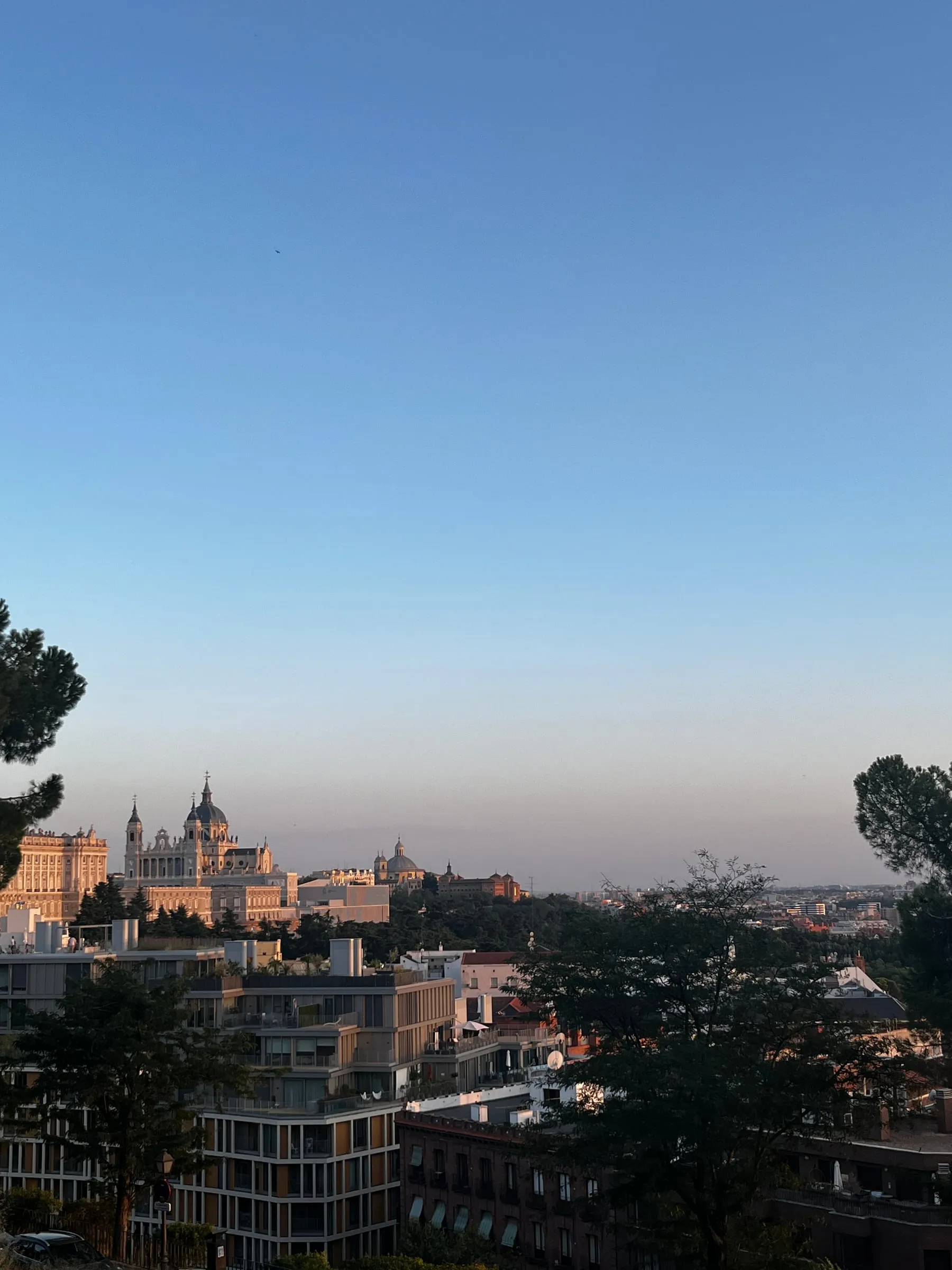 Rooftops and a distant domed building beneath a clear evening sky in Madrid.