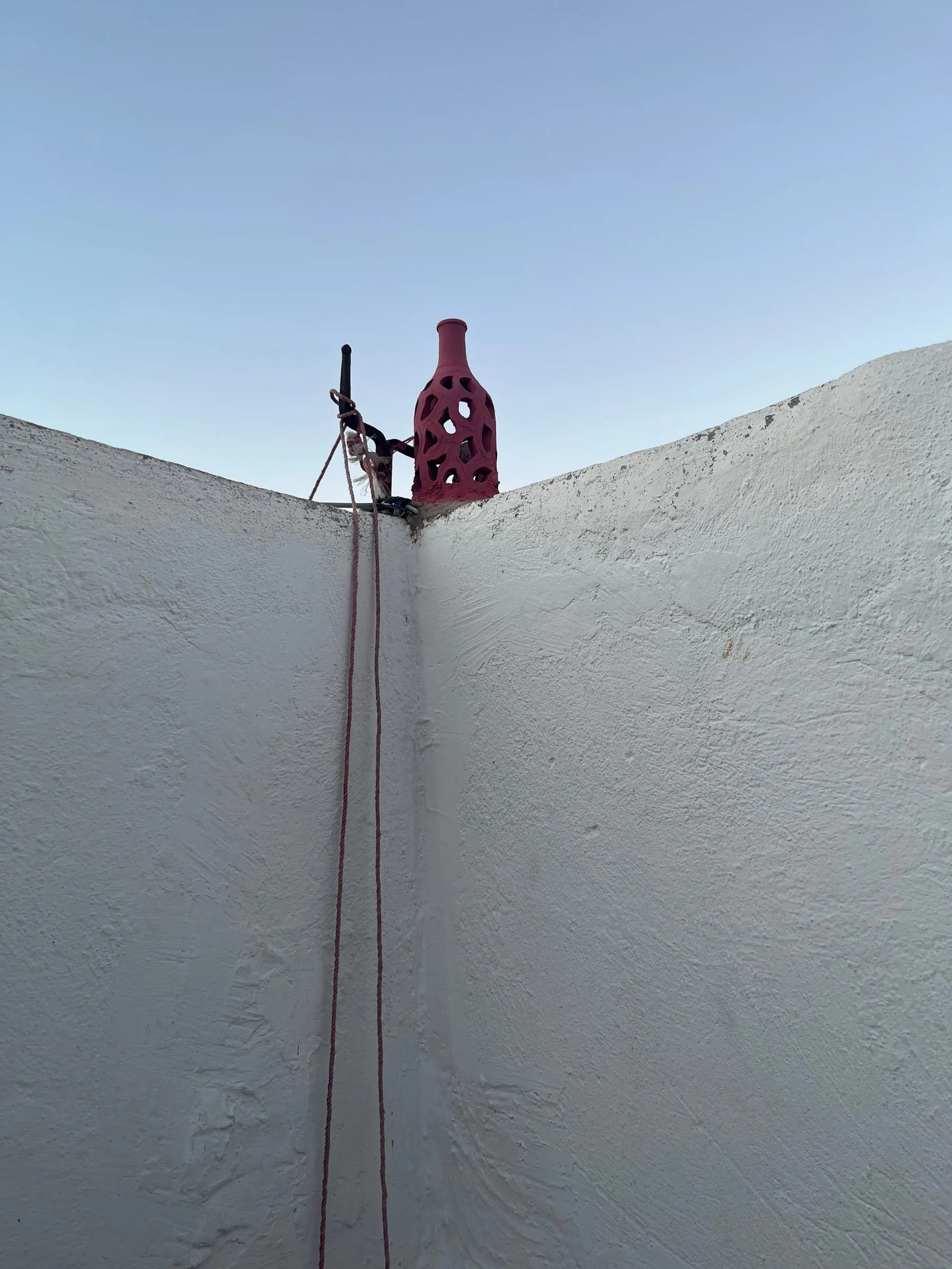 A red decorative bottle above the corner of two white courtyard walls.