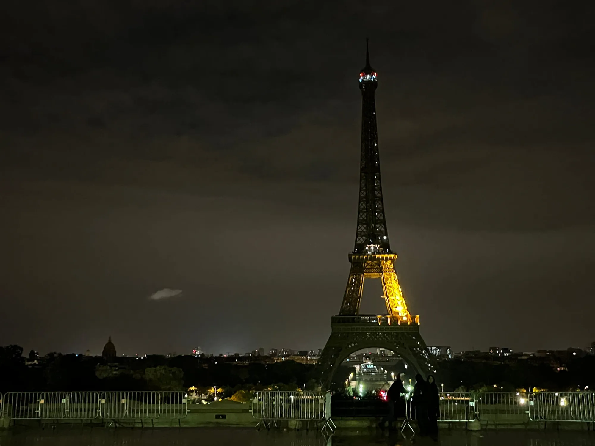The illuminated Eiffel Tower rising above visitors at night.