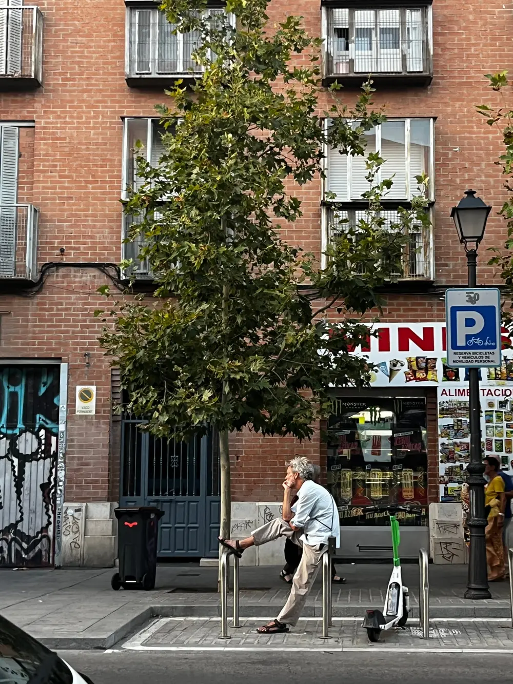 A person walking a dog past a brick building and a street sign.