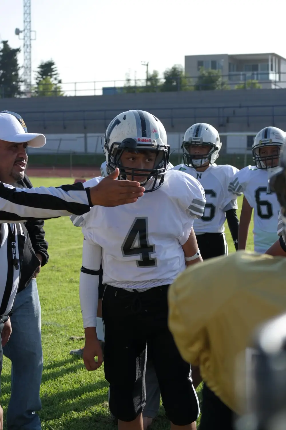 An American football player wearing a white number 4 jersey on the sideline.