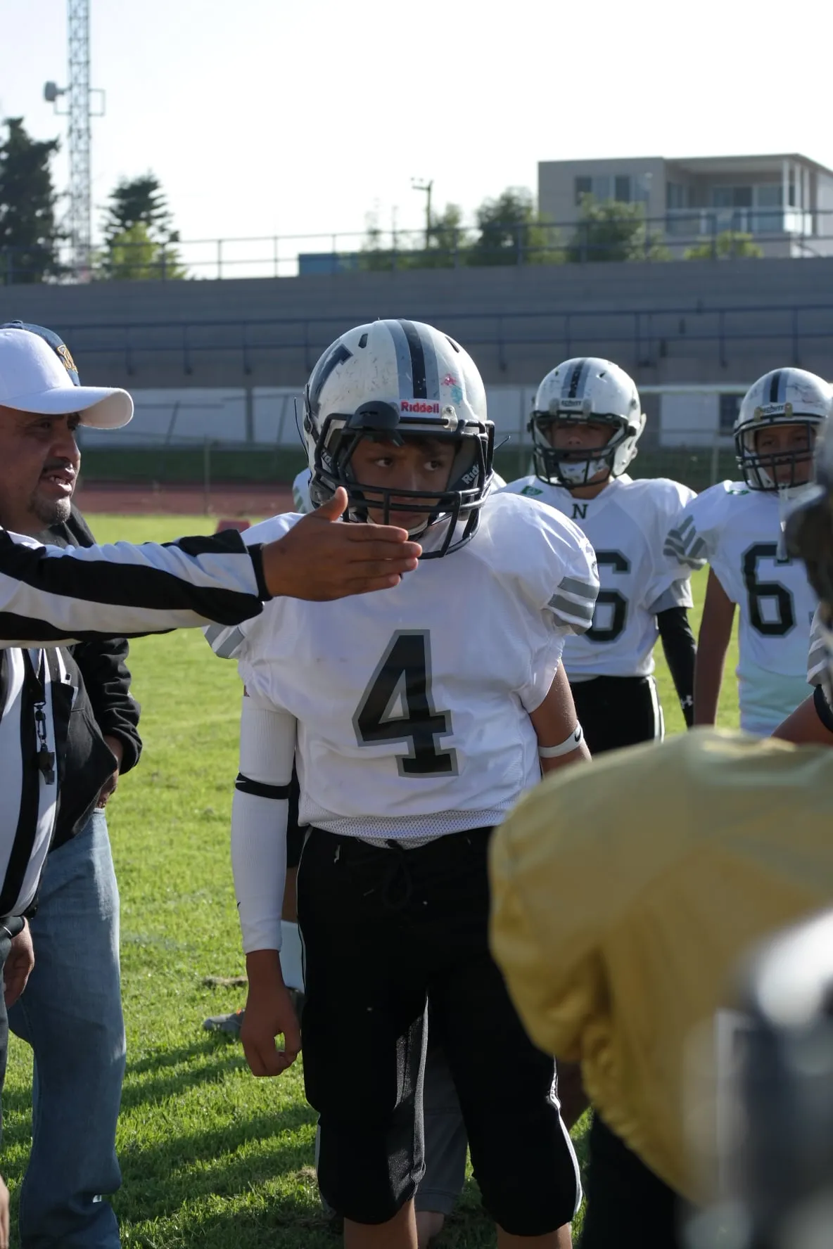 An American football player wearing a white number 4 jersey on the sideline.